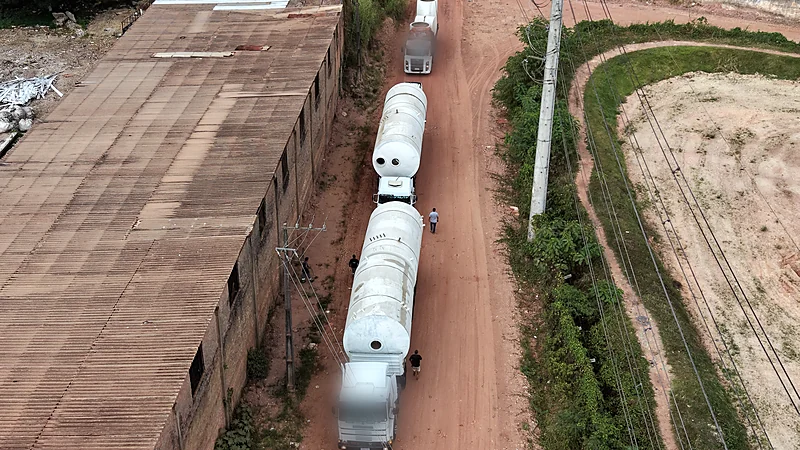 Comboio de caminhões com tanques de PRFV brancos em estrada de terra, visto de drone